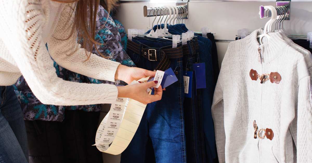 Woman places different price tags on a clothes within a retail store.