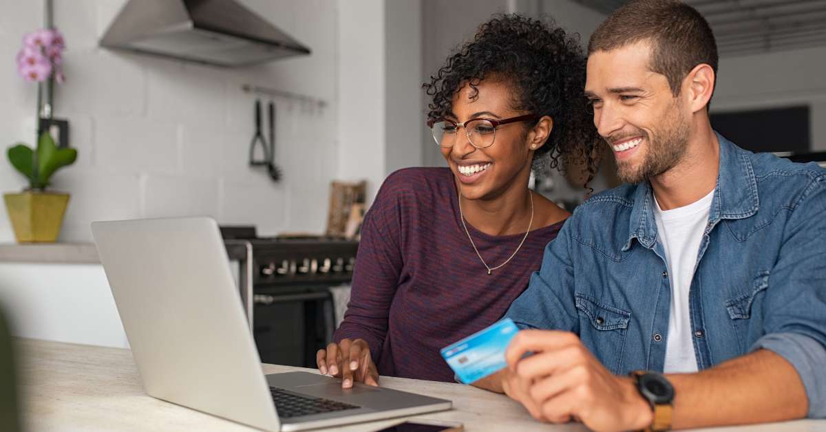 A man and woman sits at a computer to purchase some items online from a retailer using a credit card payment option.